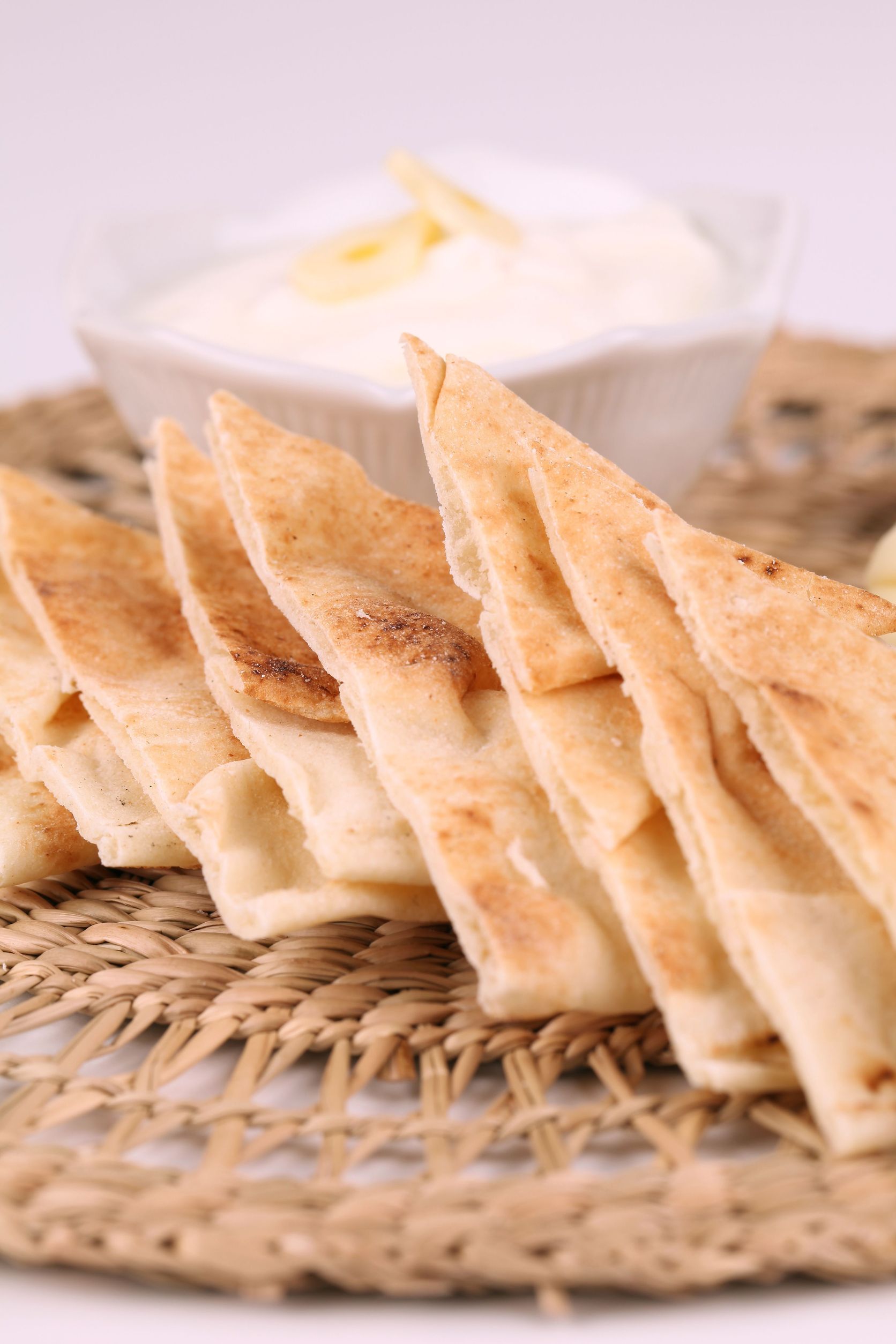 A close up of pita bread on a table with a bowl of dip in the background