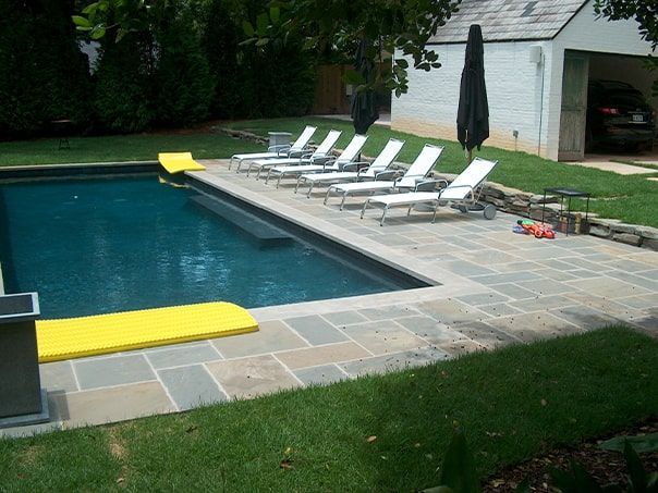 A swimming pool surrounded by lawn chairs and umbrellas