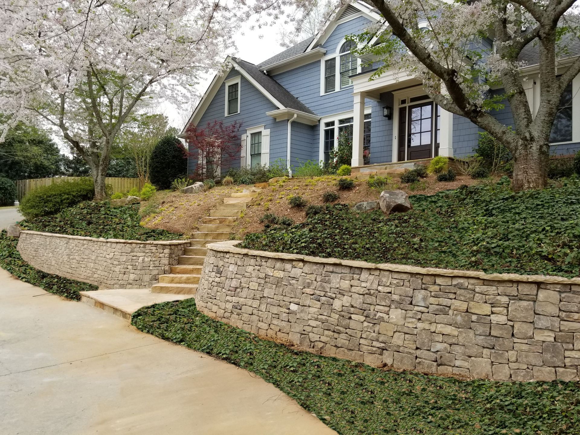 A large blue house with a stone wall in front of it.