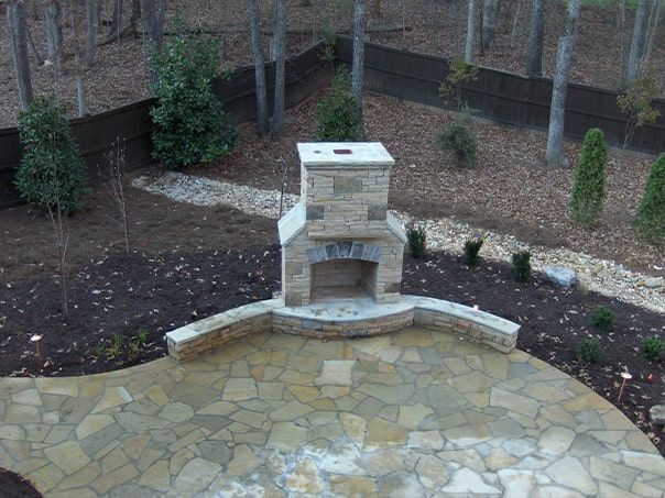 An aerial view of a patio with a fireplace and trees in the background