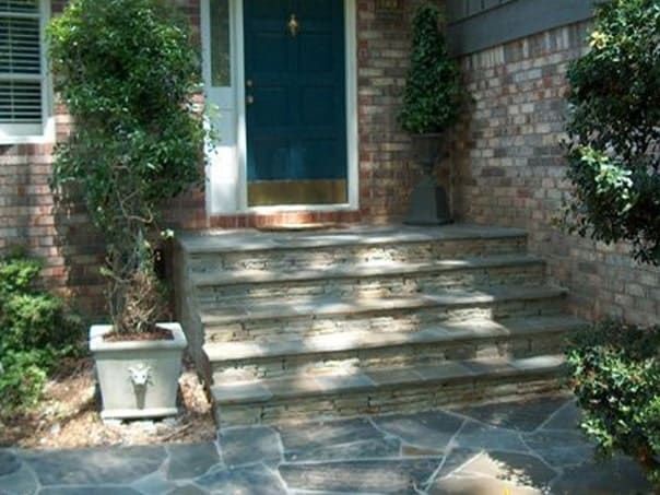 A brick house with a blue door and stone steps