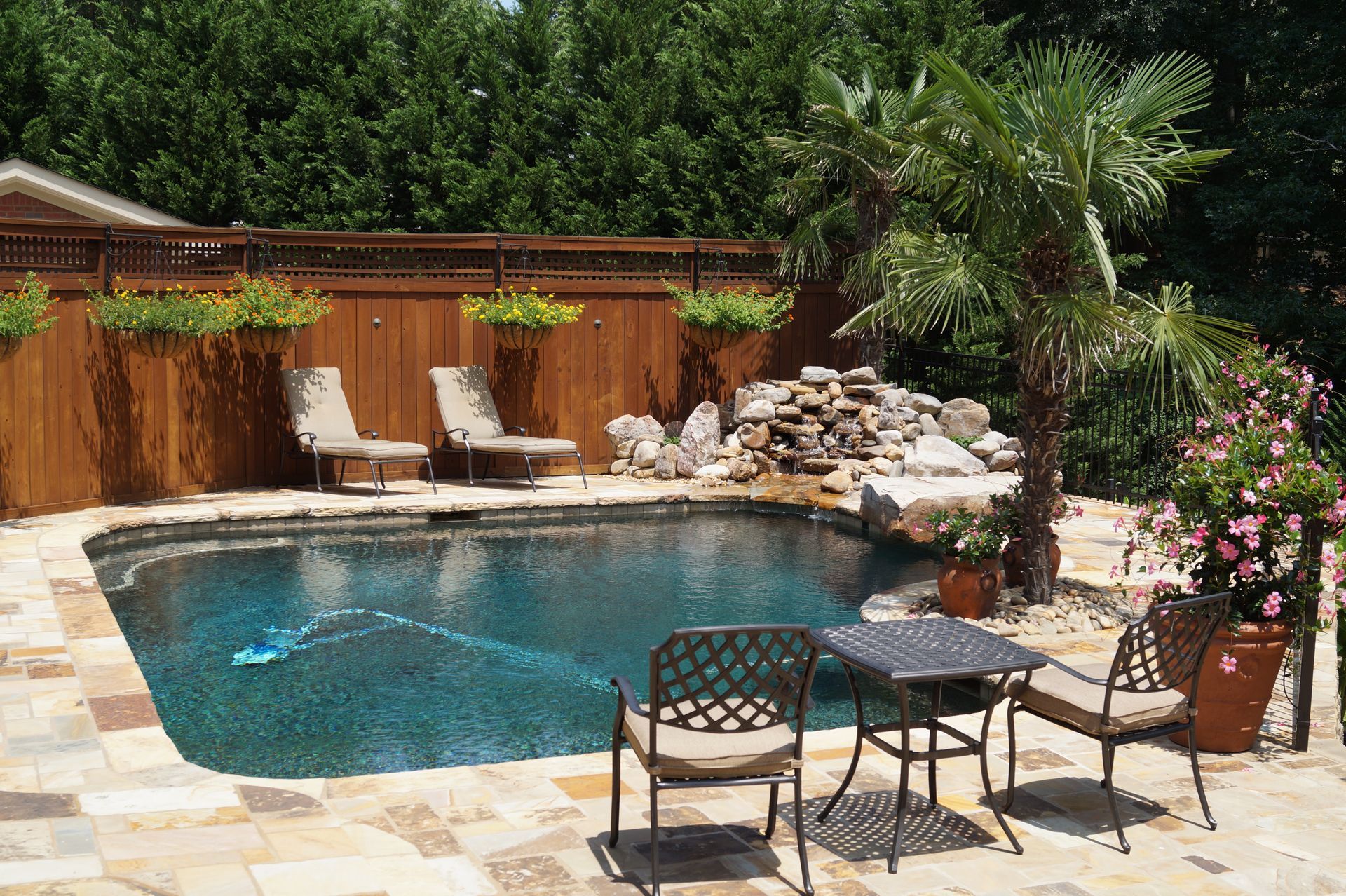 A swimming pool with chairs and a table in front of it