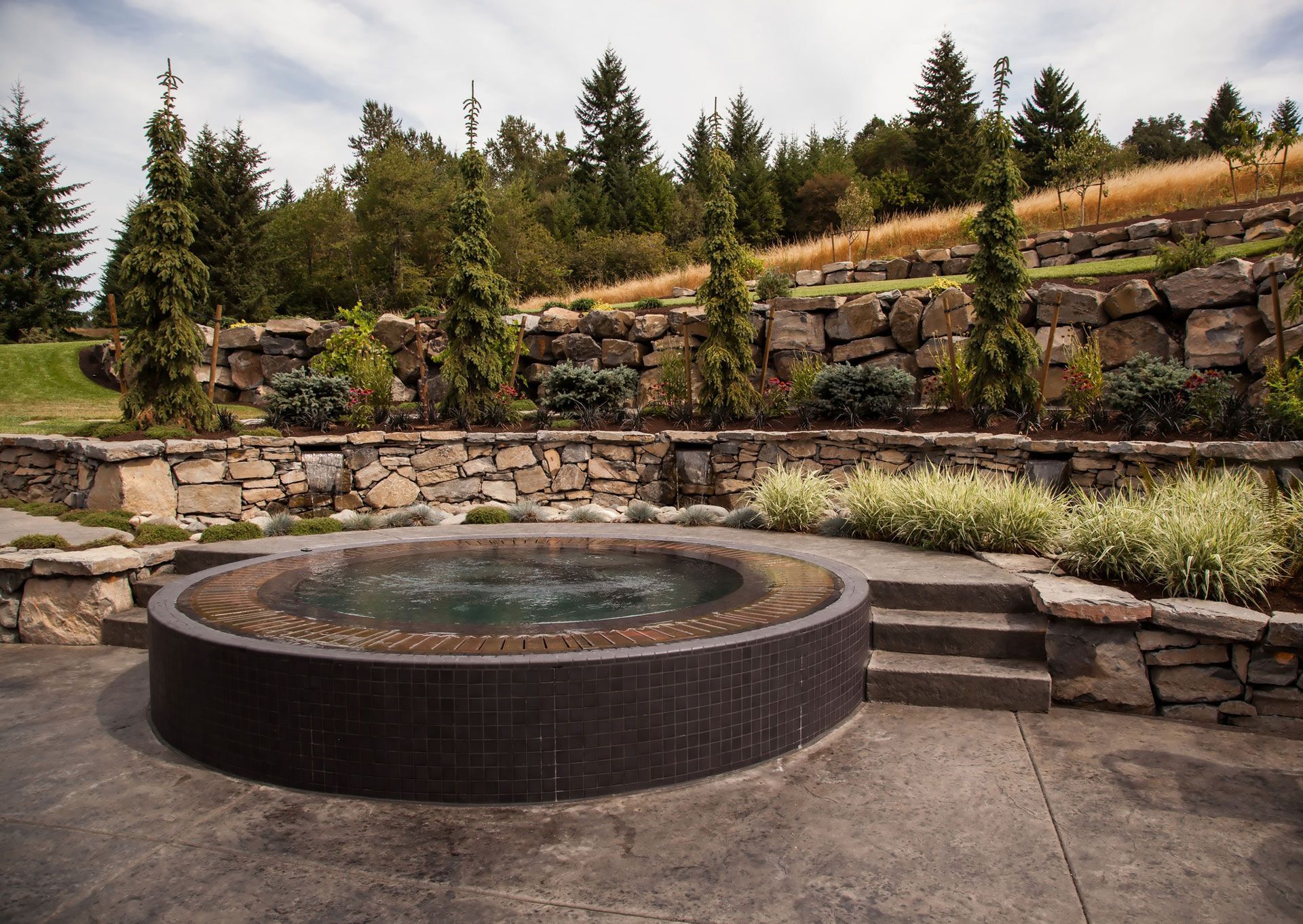 A hot tub is surrounded by stone walls and trees