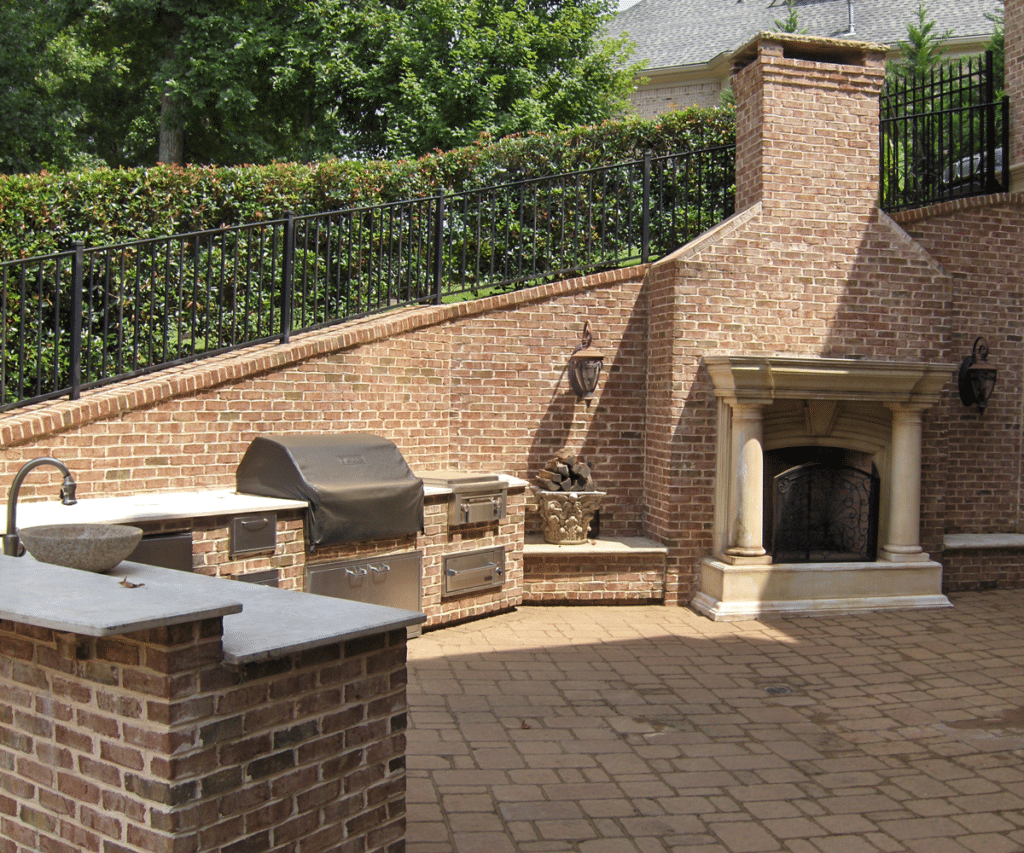 A brick patio with a grill and a fireplace