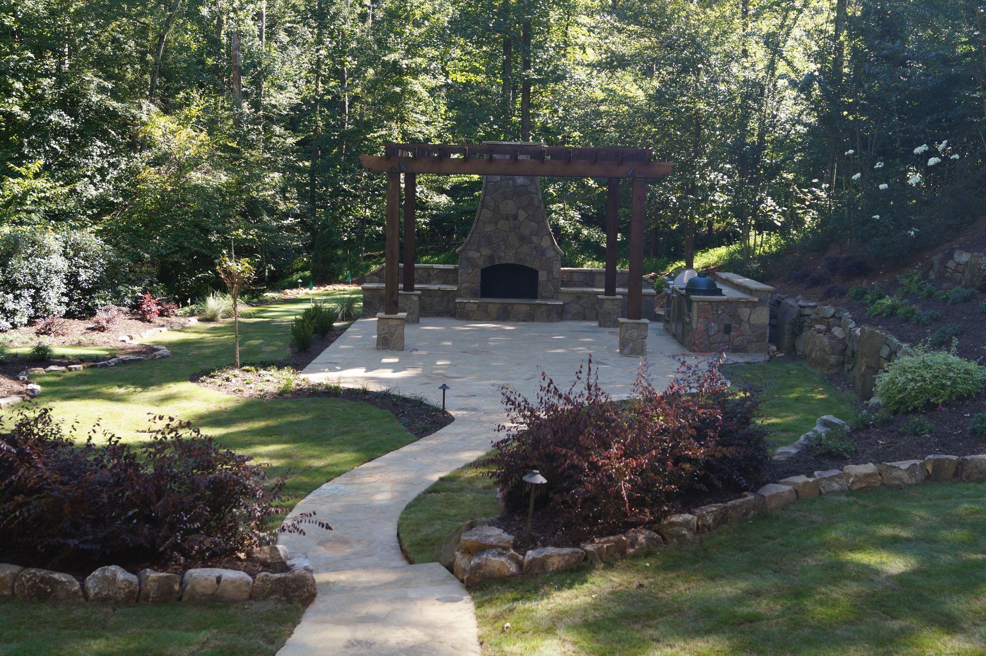 A stone walkway leading to a fireplace in a backyard