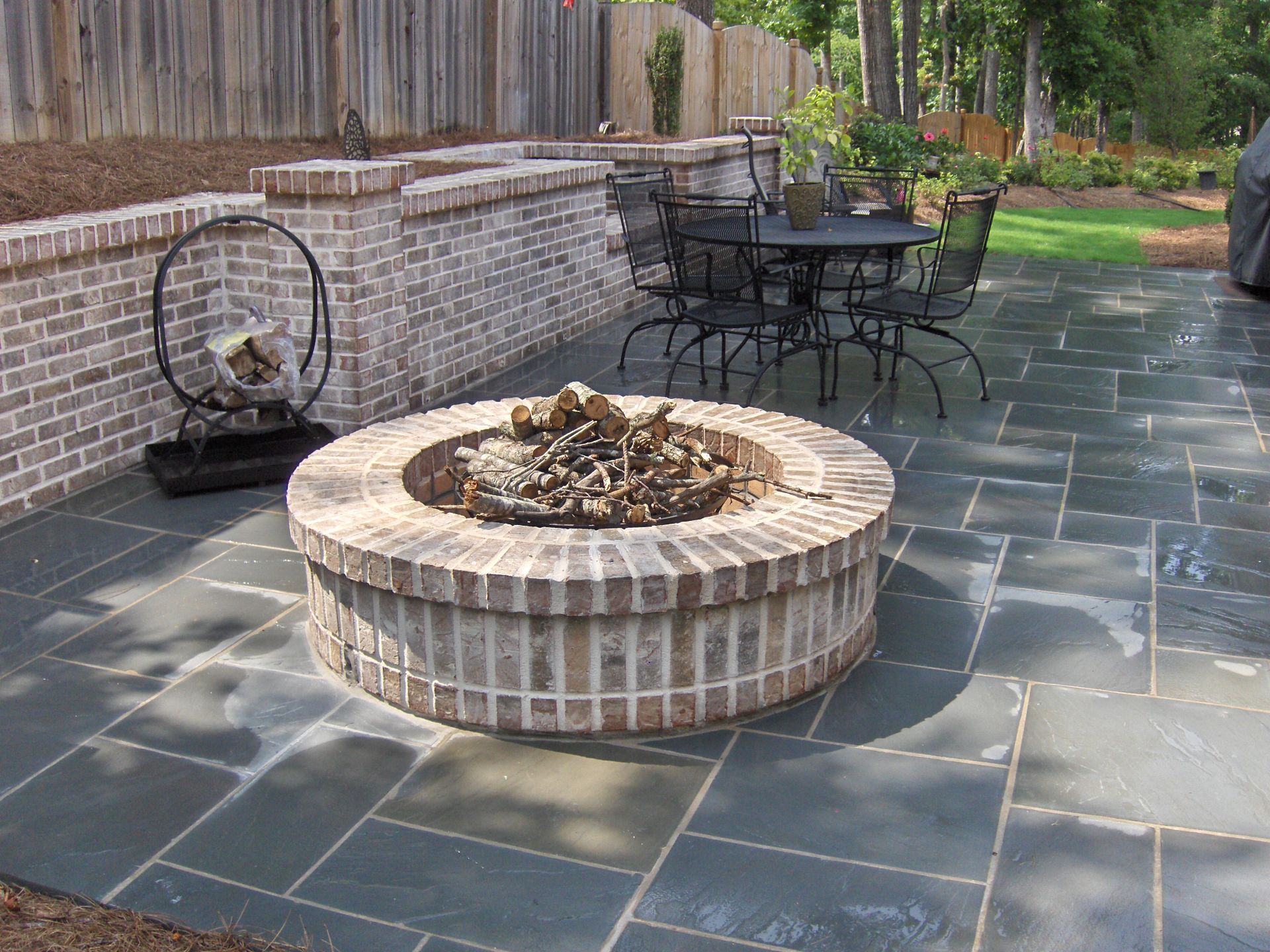 A fire pit is sitting on a patio next to a table and chairs.