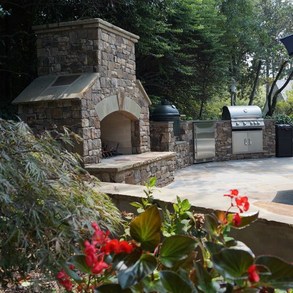 A stone fireplace with a stainless steel grill in the background