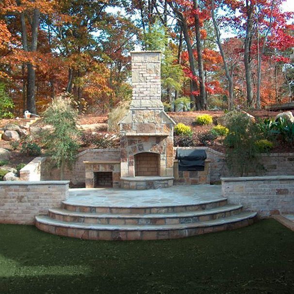 A stone fireplace with steps leading up to it and outdoor grill