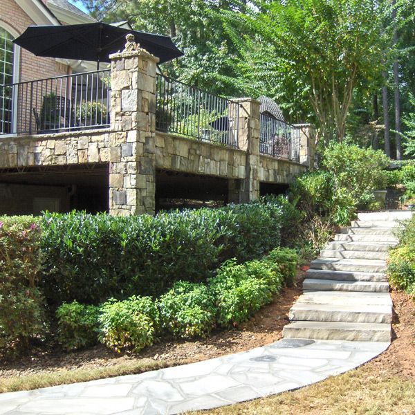 A stone walkway leading to a deck with stone columns and a black umbrella