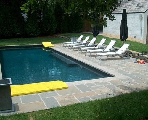 A large swimming pool surrounded by lawn chairs and umbrellas