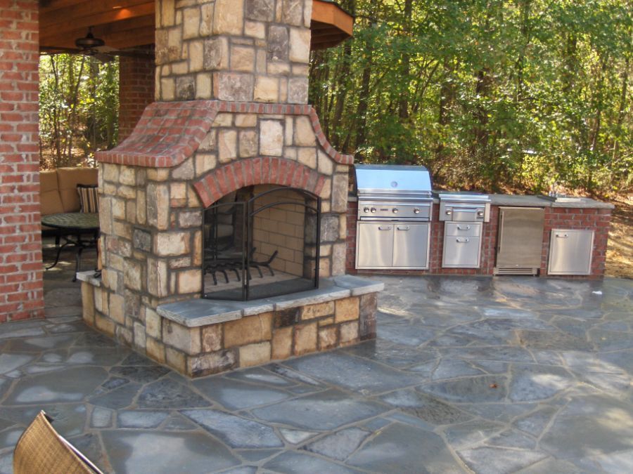 A stone fireplace with a grill in the background