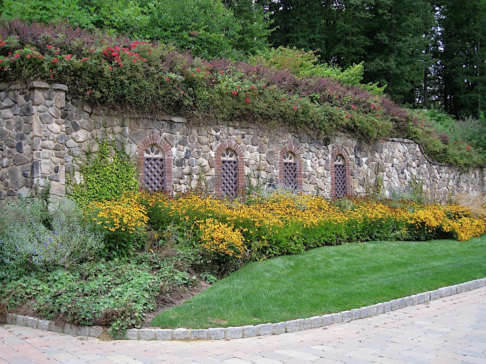 A stone wall with flowers and shrubs growing on it