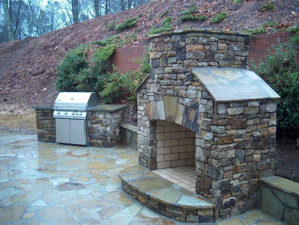 A stone fireplace with a grill next to it