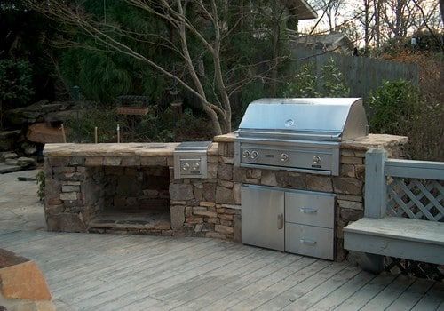 A stainless steel grill is sitting on top of a wooden deck.