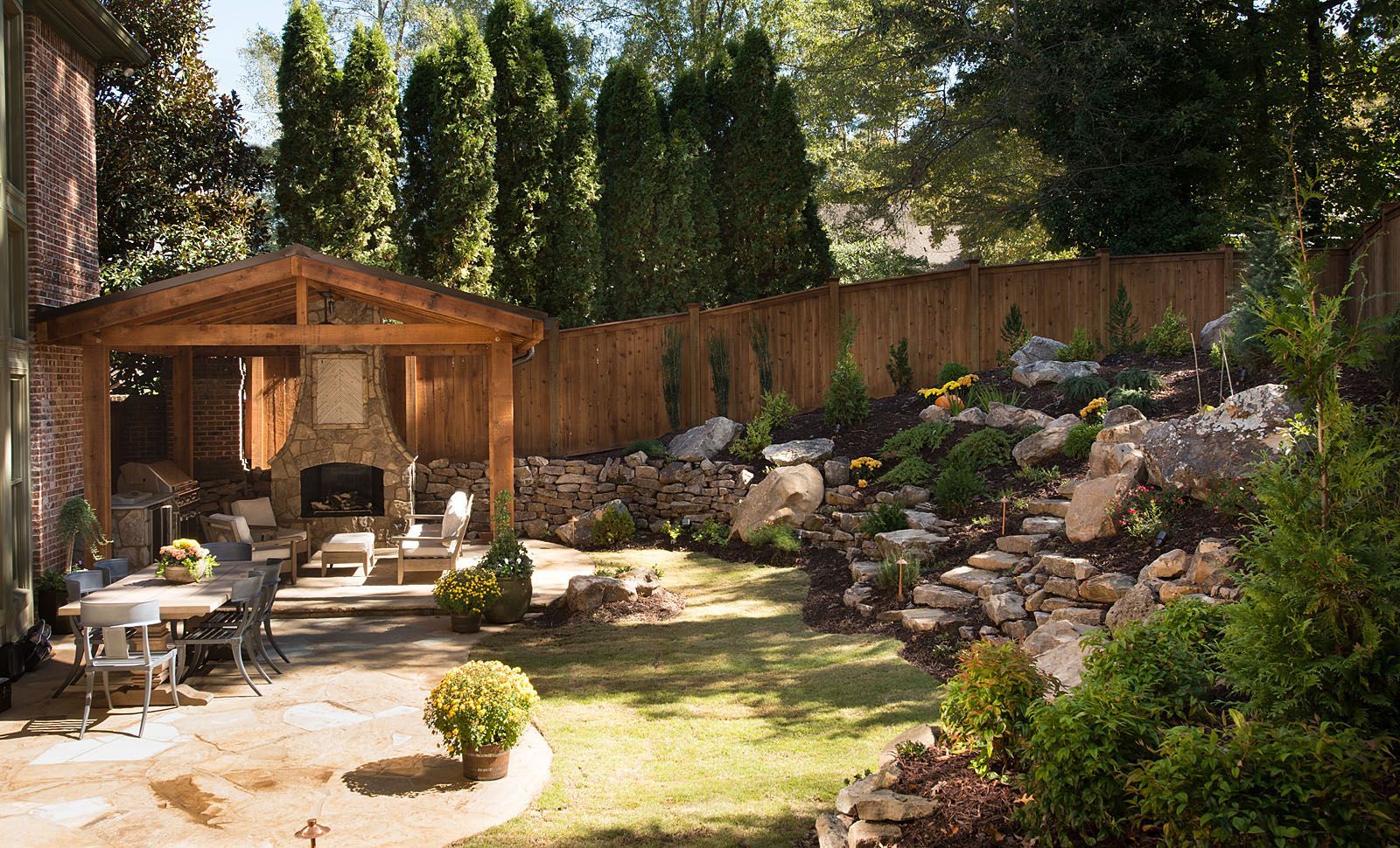 A backyard with a wooden pavilion and a fireplace