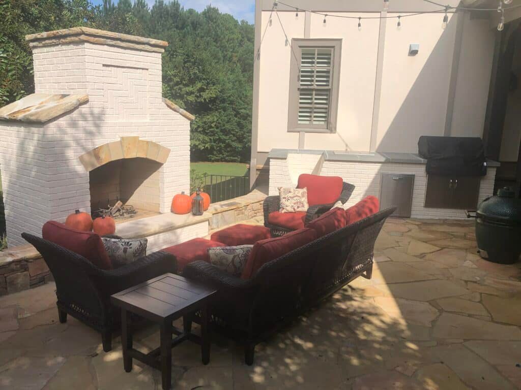 A patio with a fireplace , couch , chairs and pumpkins.