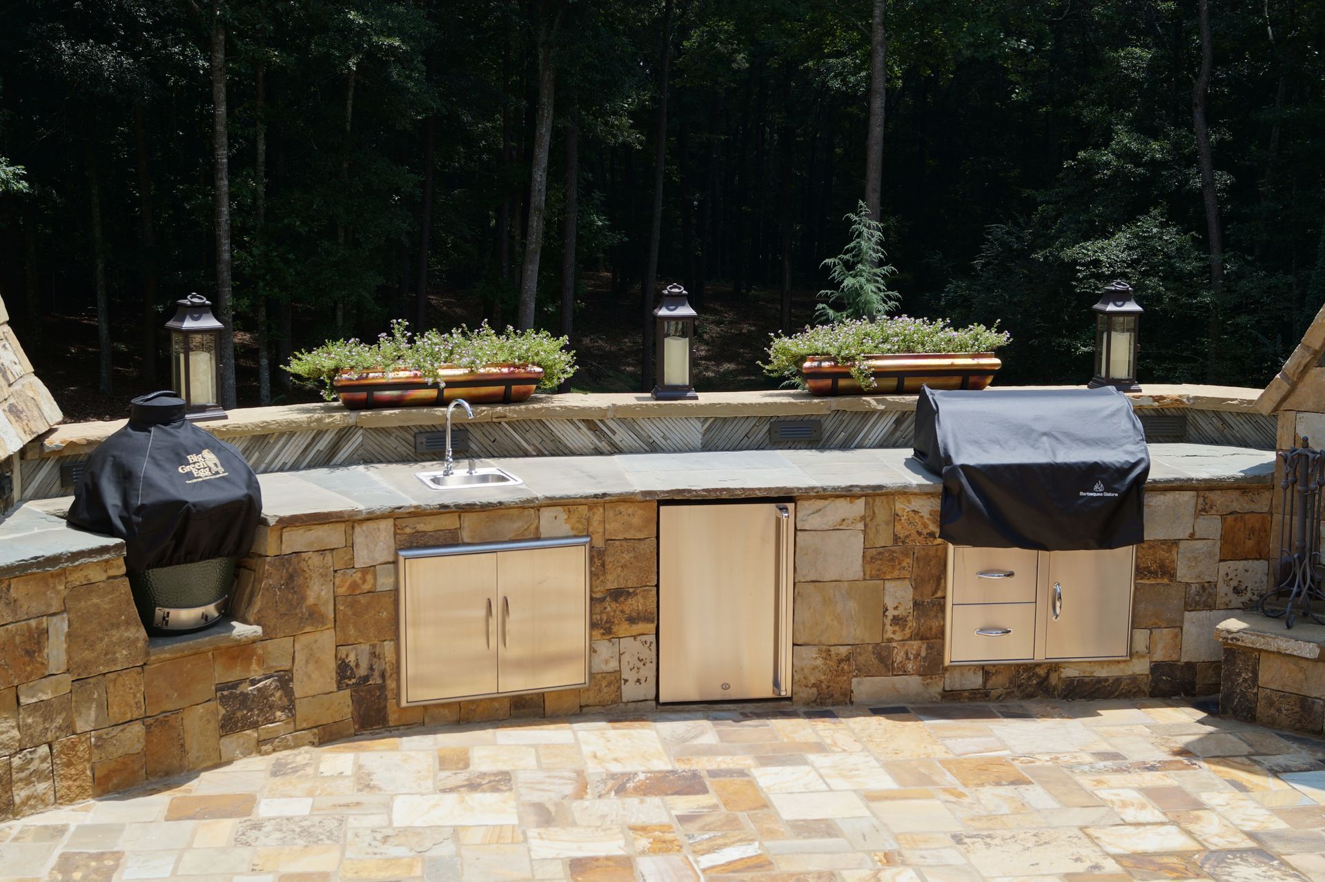 A large outdoor kitchen with a grill and a sink