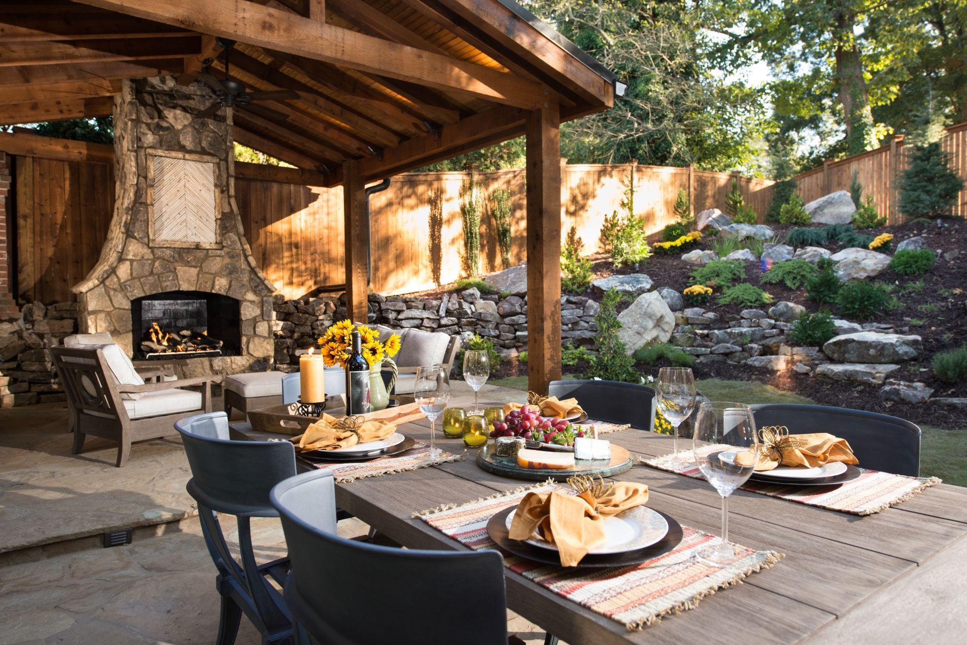 A patio with a table and chairs and a fireplace and  cedar pavilion.