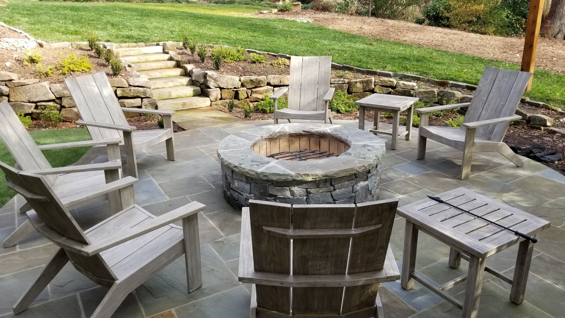 A group of chairs are sitting around a fire pit on a patio.