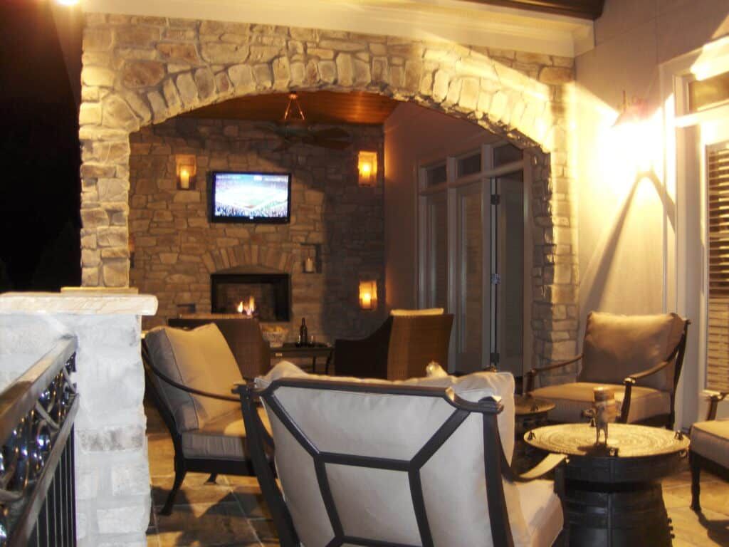 A patio with a fireplace and a flat screen tv and arched stone walls