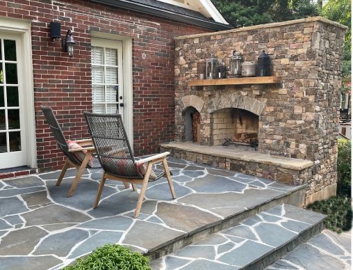 There is a fireplace in the backyard of a brick house.