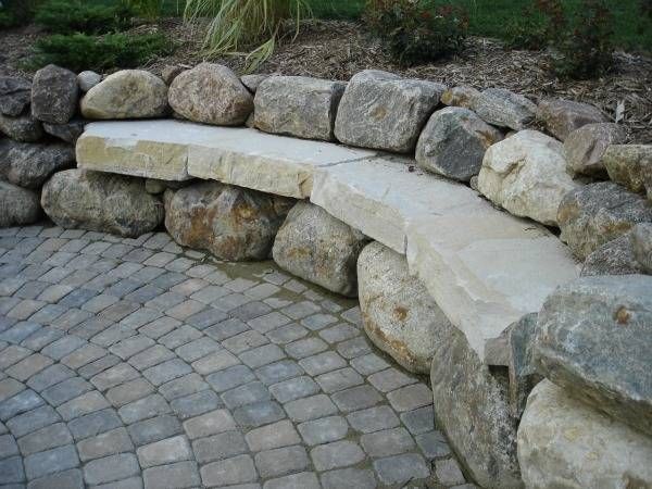 A CUSTOM BUILT MASONRYstone wall with a bench built into it