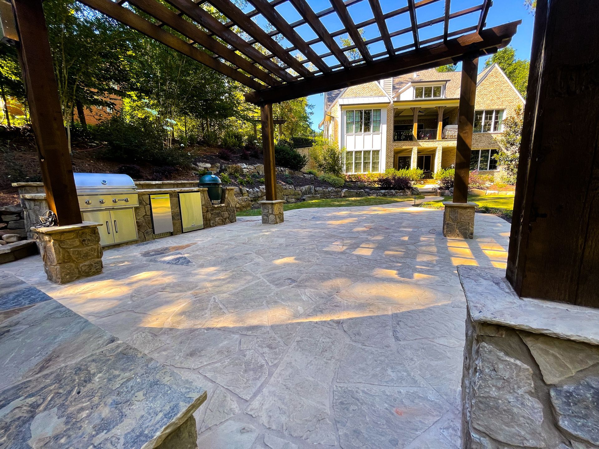 A patio with a pergola and a large house in the background.