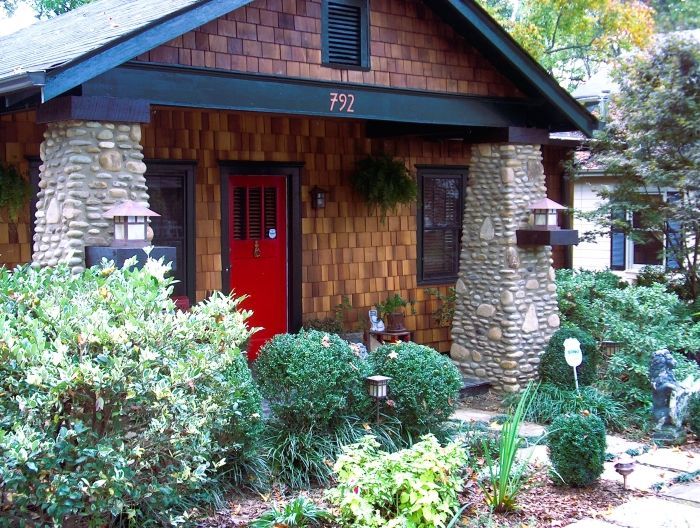 A house with battered river rock and mortar entranceway columns. A stone stack pattern. 