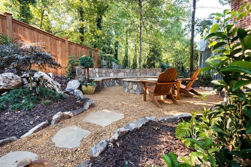 A backyard with a wooden fence , chairs , a table and a bench.