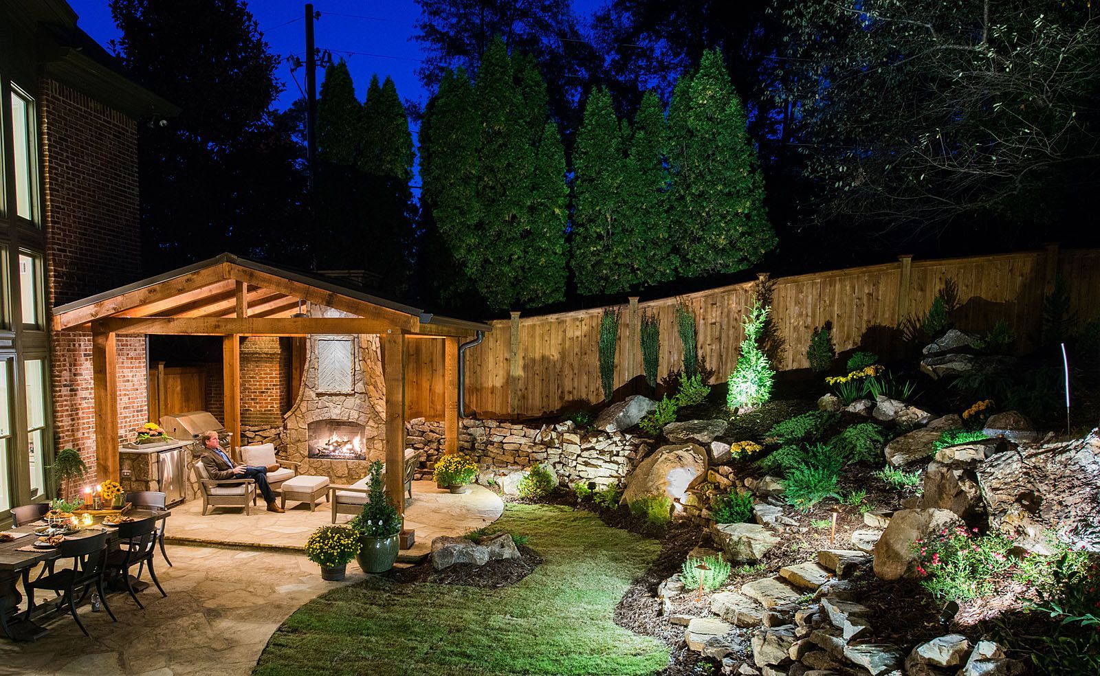A backyard with a fireplace and a patio at night.