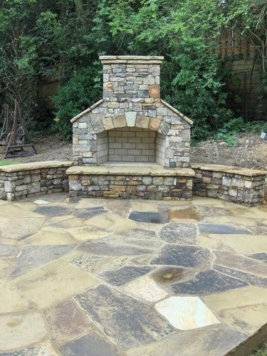 A stone fireplace is sitting on top of a stone patio.