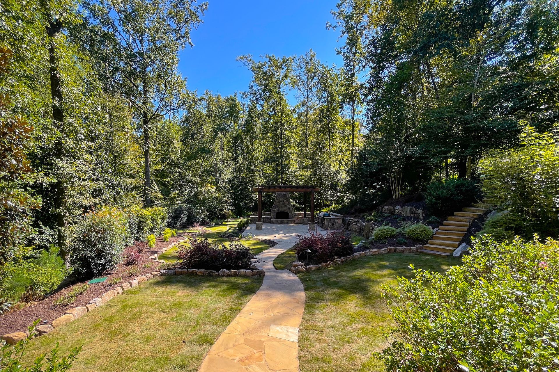 A path leading to a gazebo in the middle of a lush green garden.