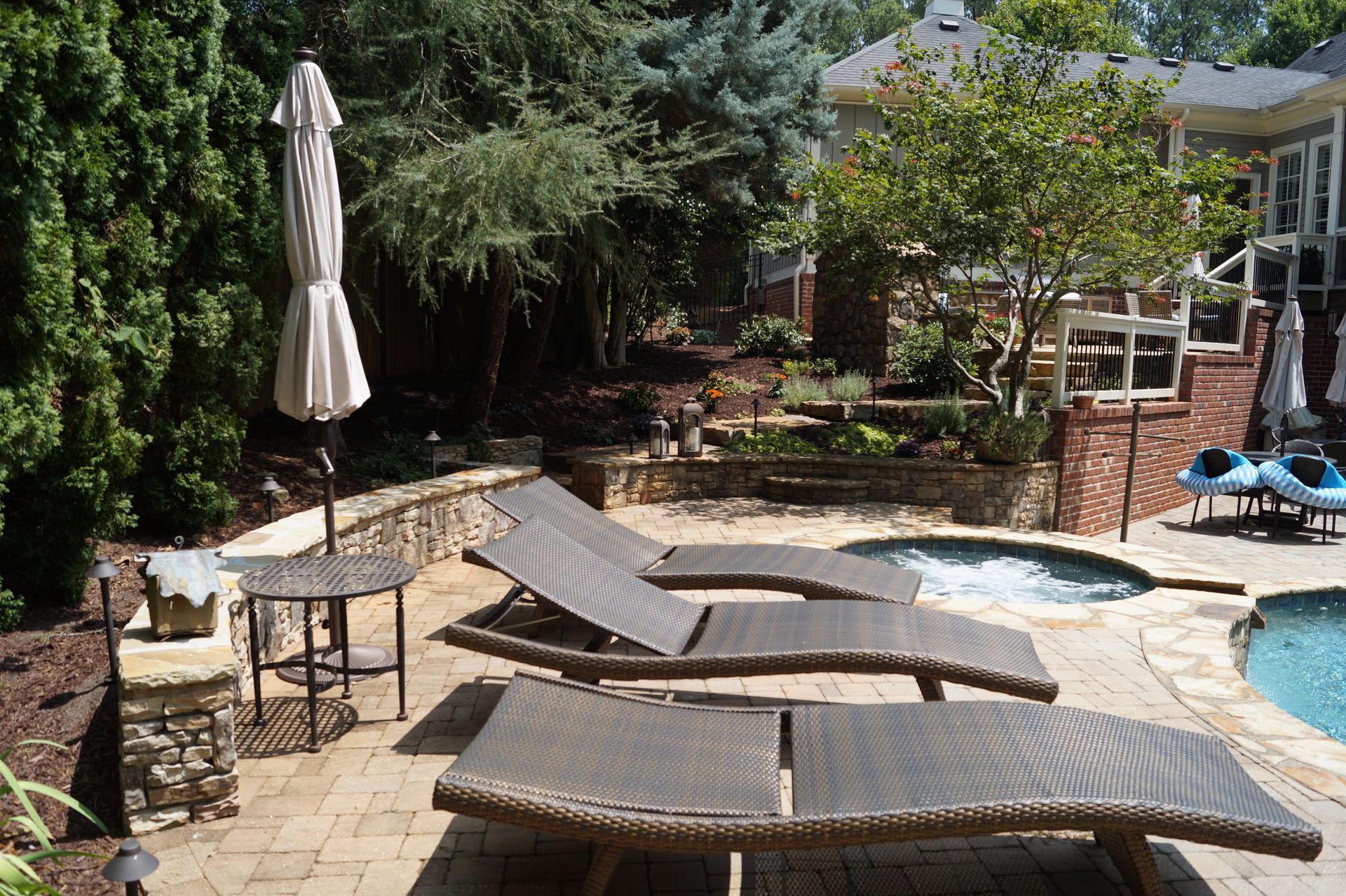 A patio with lounge chairs and an umbrella next to a pool