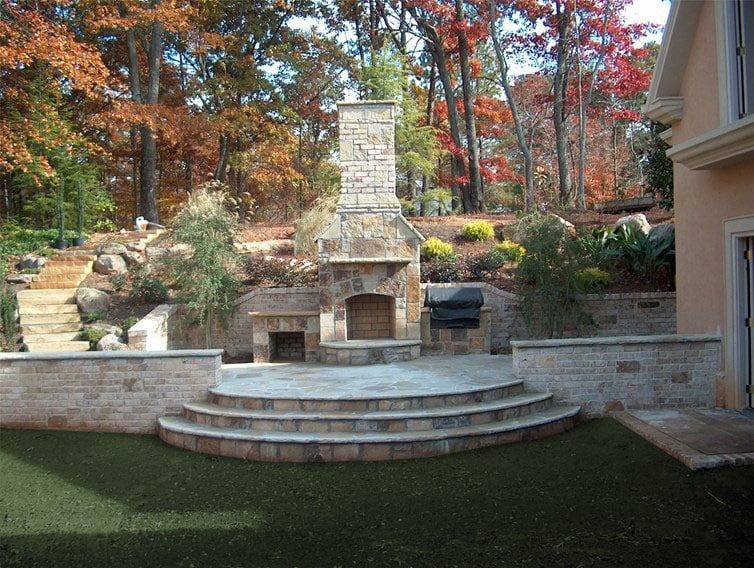 A stone fireplace sits in the backyard of a house