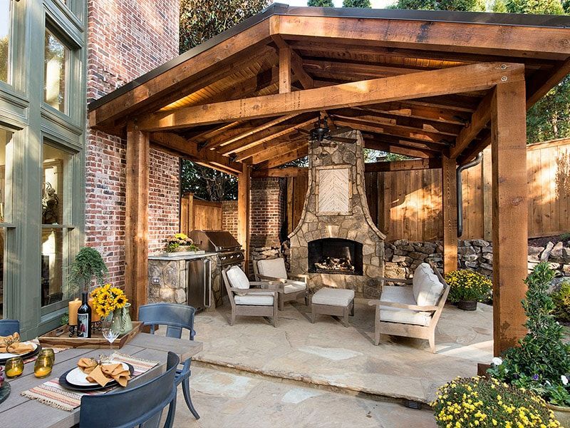 A patio with a wooden pavilion and a fireplace.
