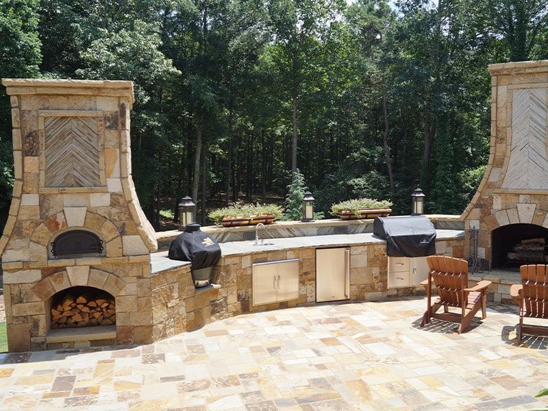 A patio with a pizza oven and a fireplace
