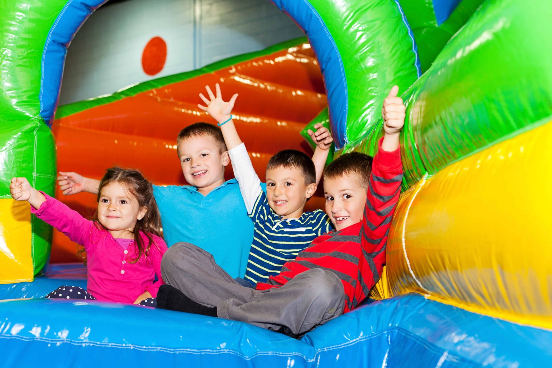 A group of children are sitting on top of a bouncy house.