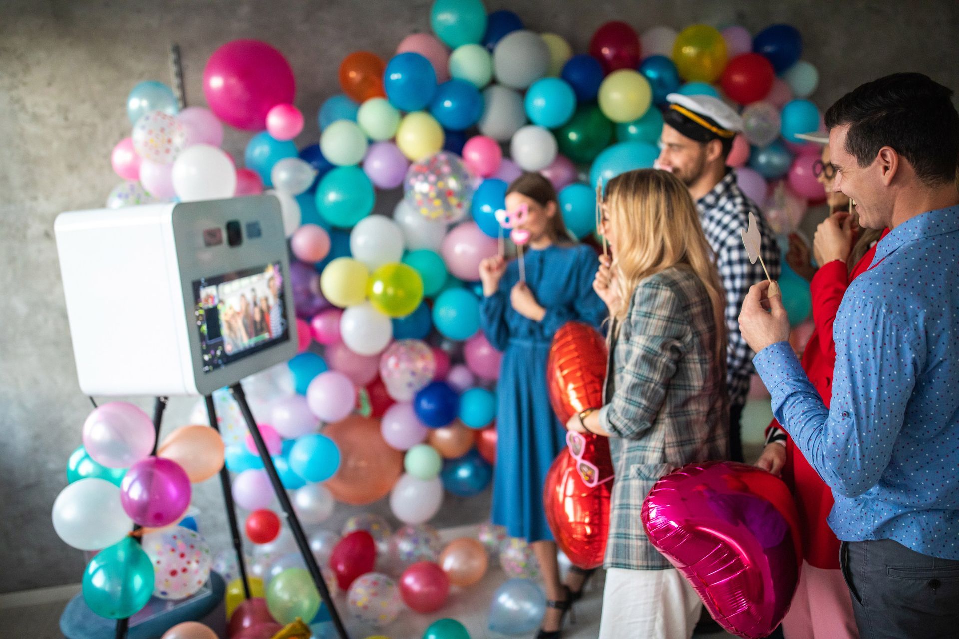 A group of people are posing for a picture in front of a wall of balloons.