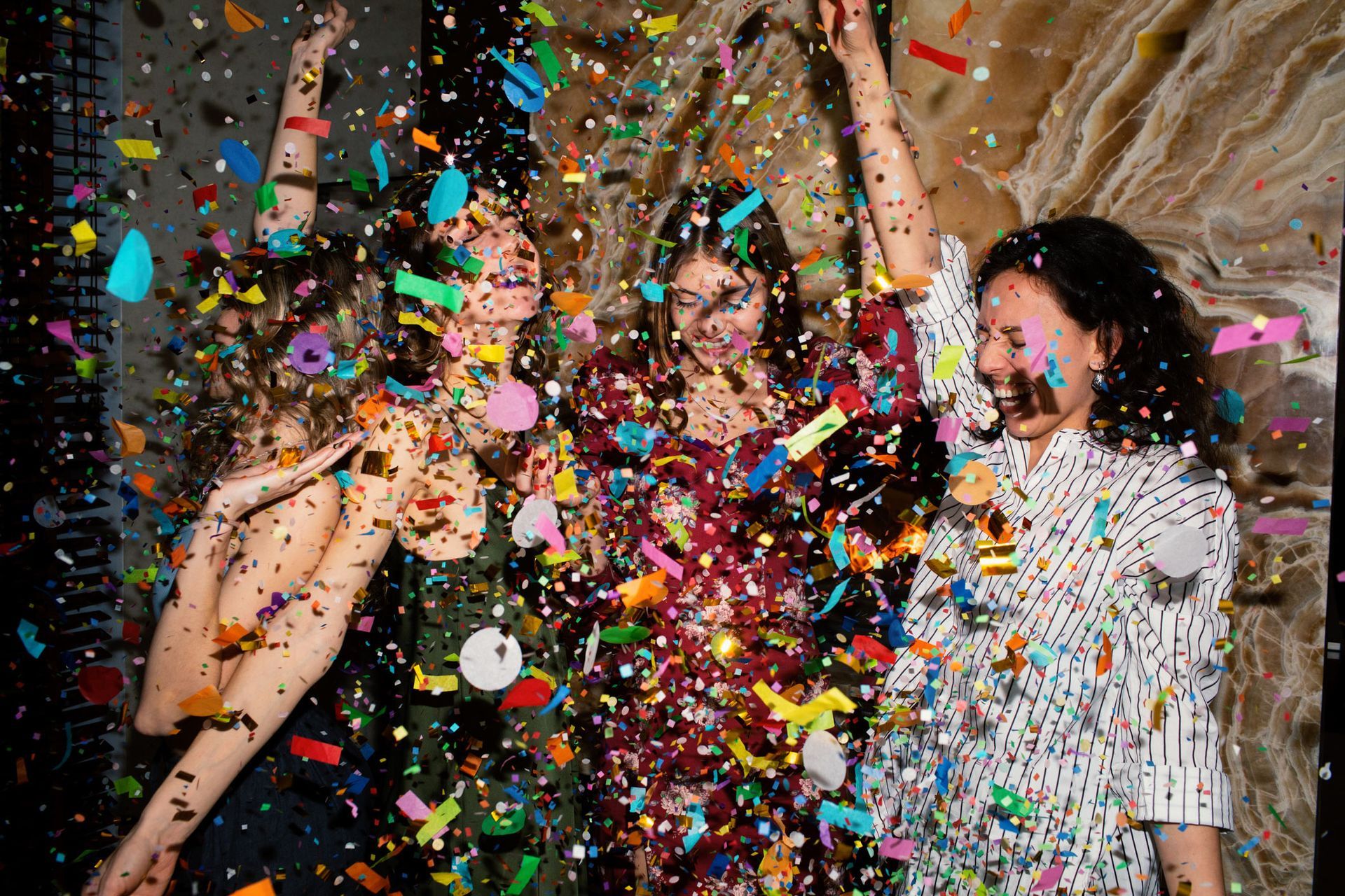 Three women are laying on the floor covered in confetti.