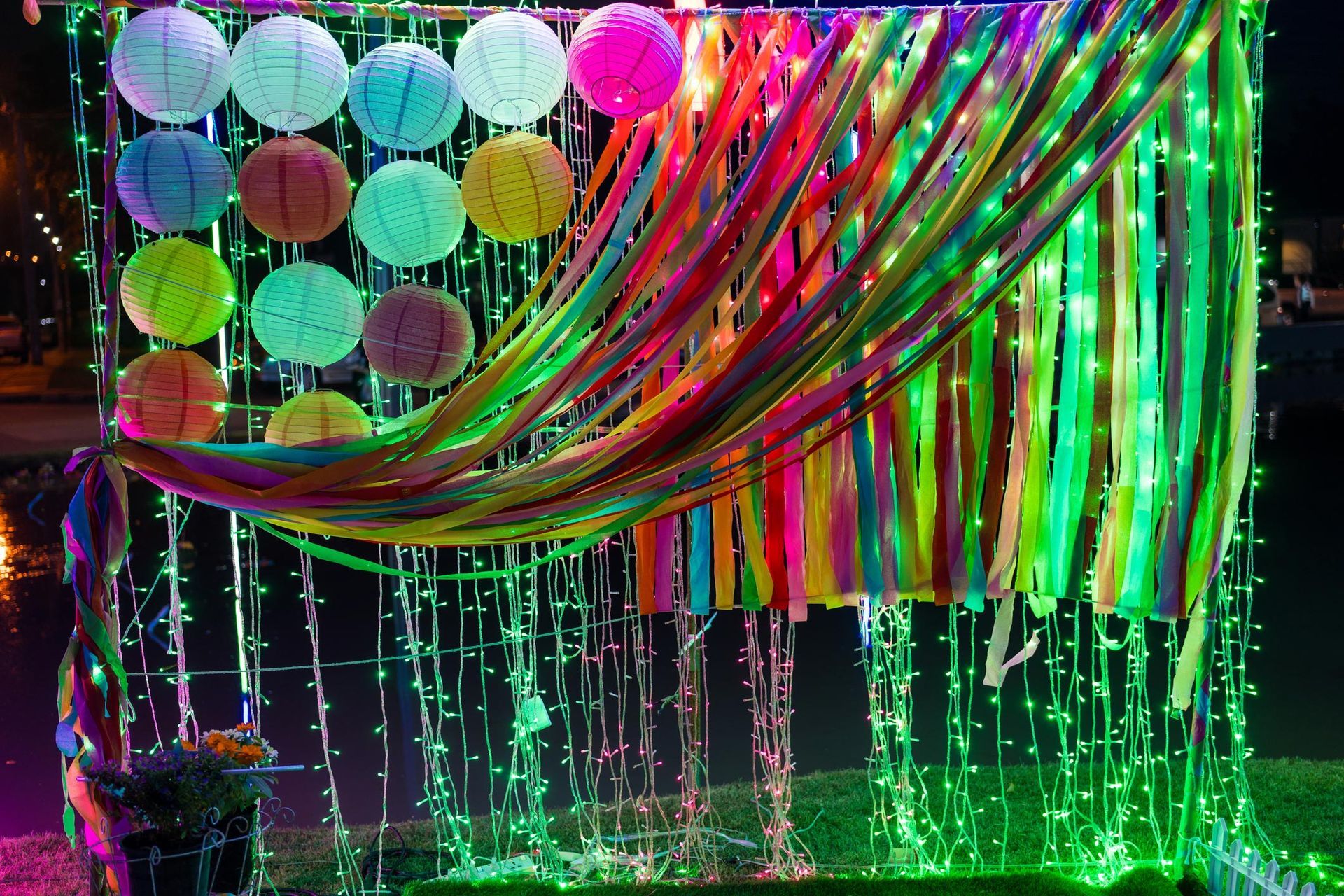 A bunch of colorful ribbons and lanterns are hanging on a wall.