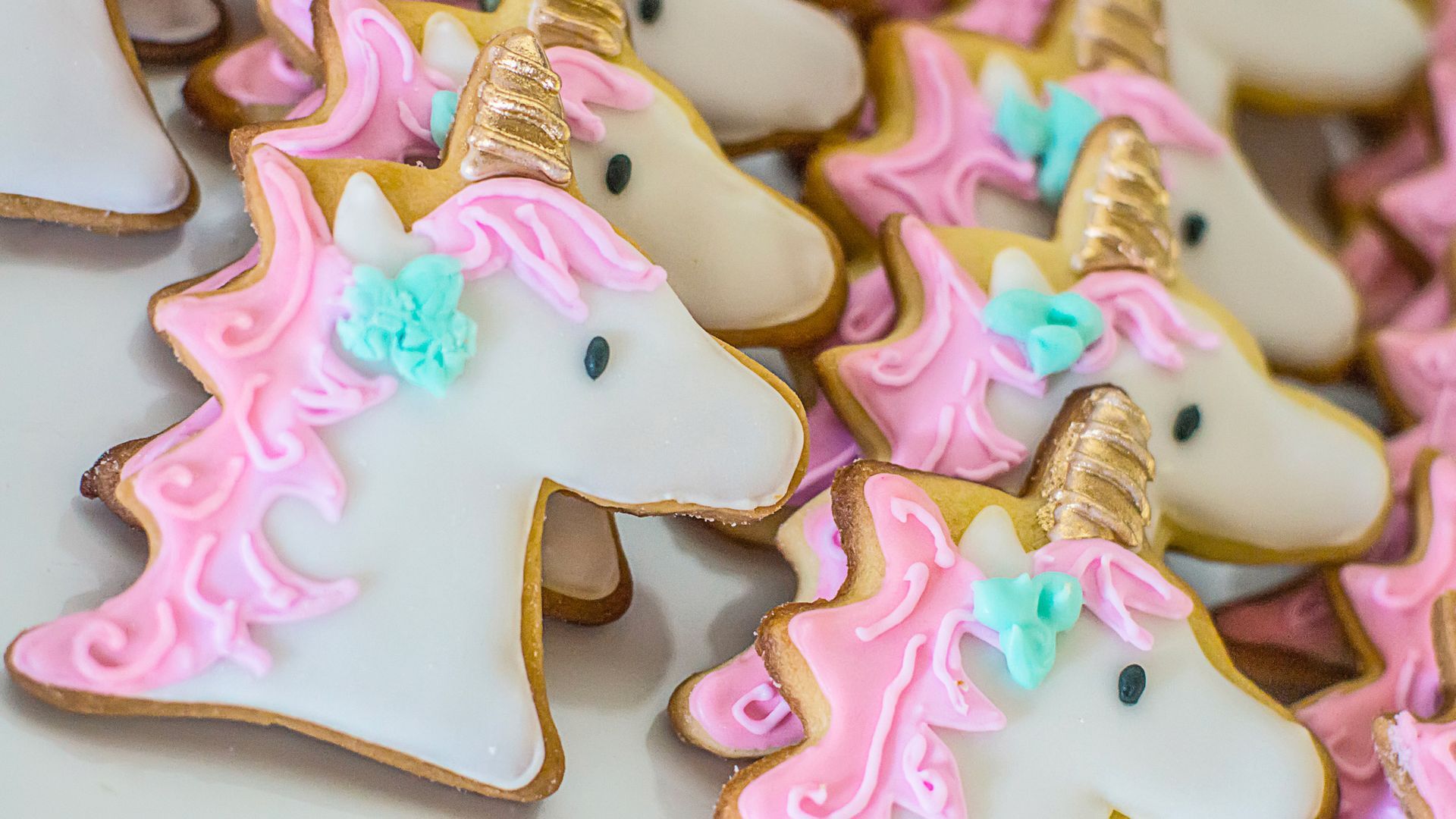 A bunch of unicorn cookies are sitting on top of each other on a table.