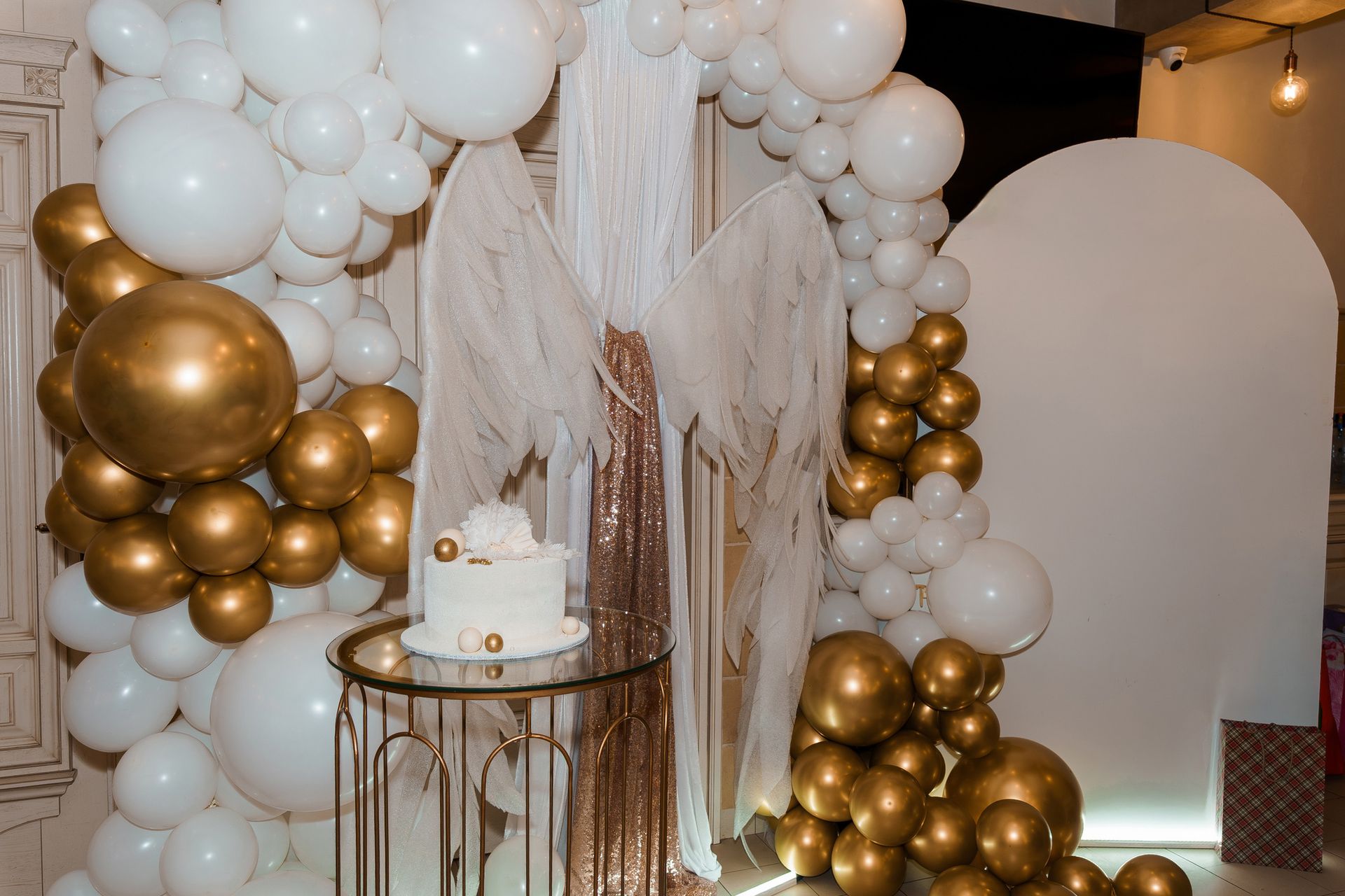 A table with a cake on it is surrounded by balloons.