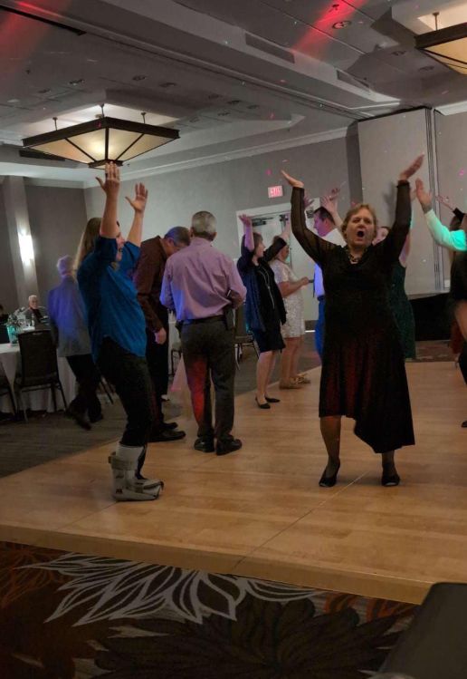A group of people are dancing on a dance floor in a room.