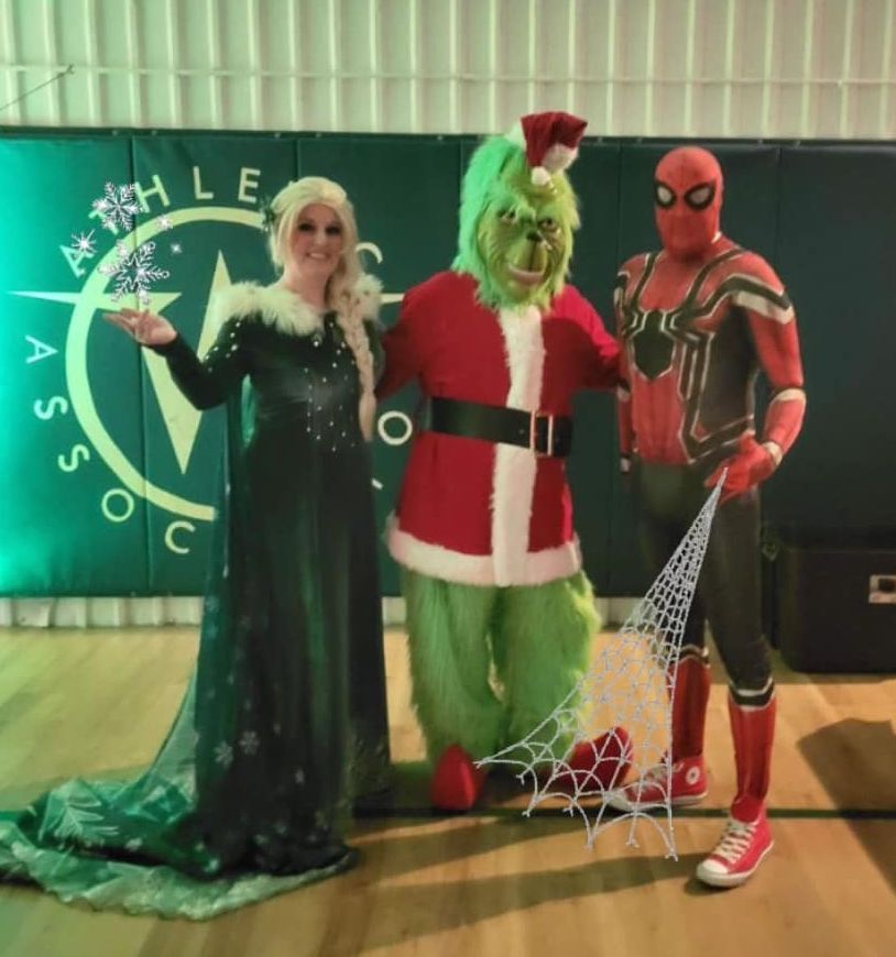 A group of people in costumes pose in front of a sign that says athletic association.