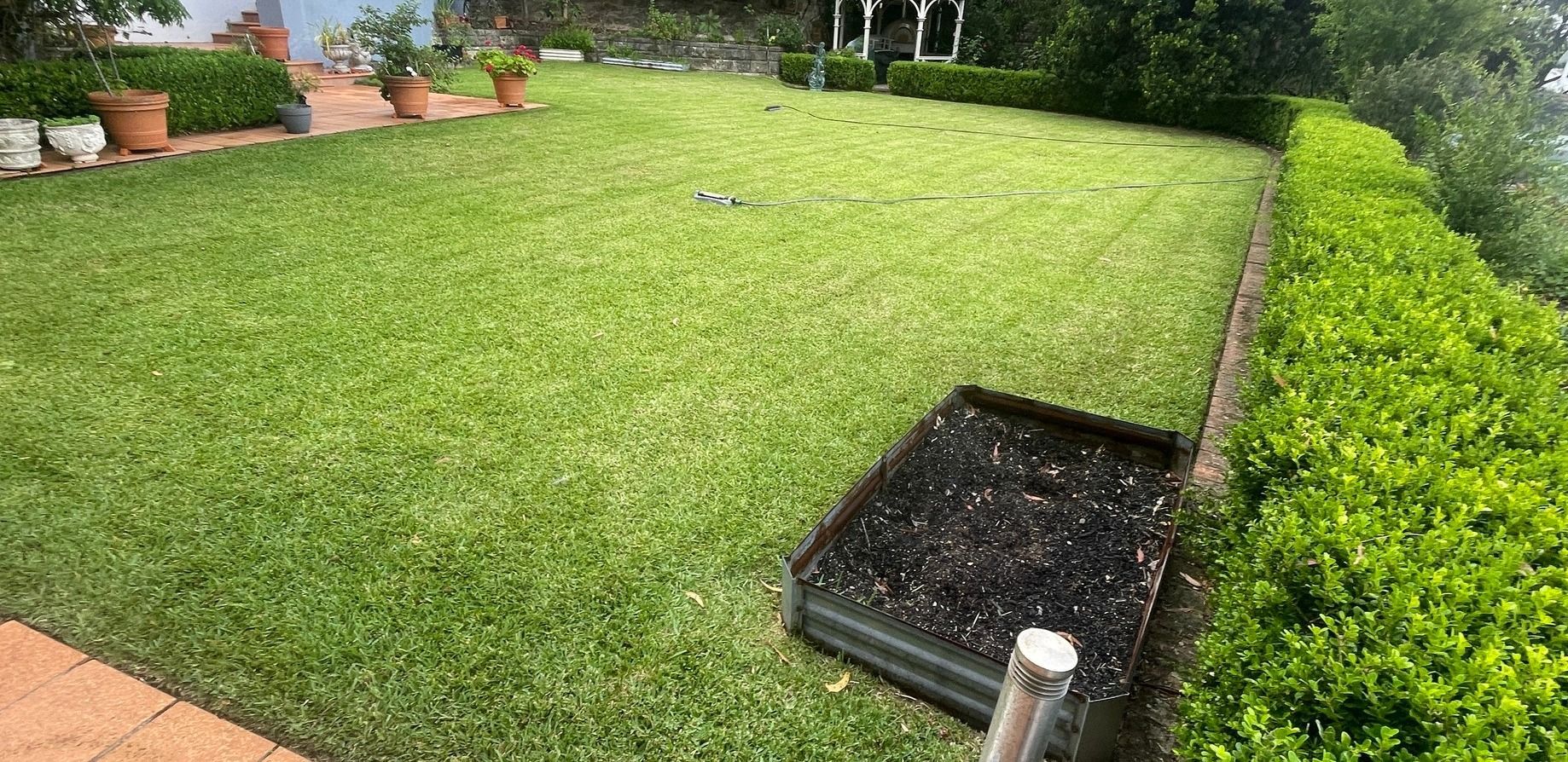 Parking area with low hedge in front of a building.