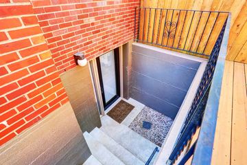 A brick wall with stairs leading up to a basement door.