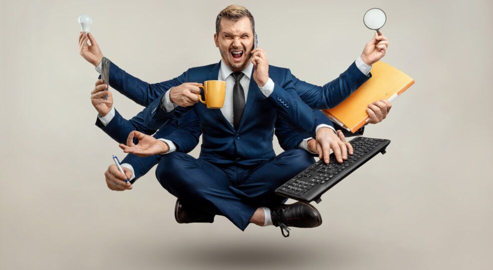 Een man in pak zit in lotushouding met vele handen.