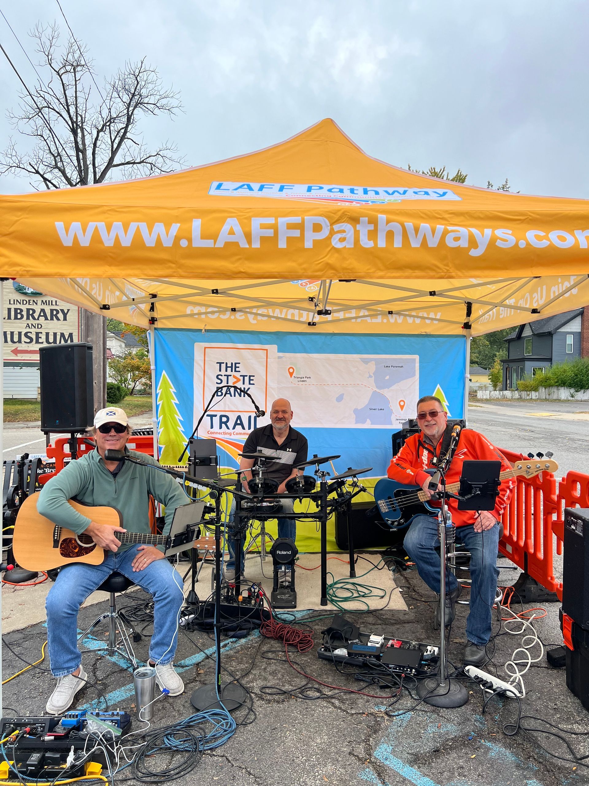A group of men are playing instruments under a yellow tent.