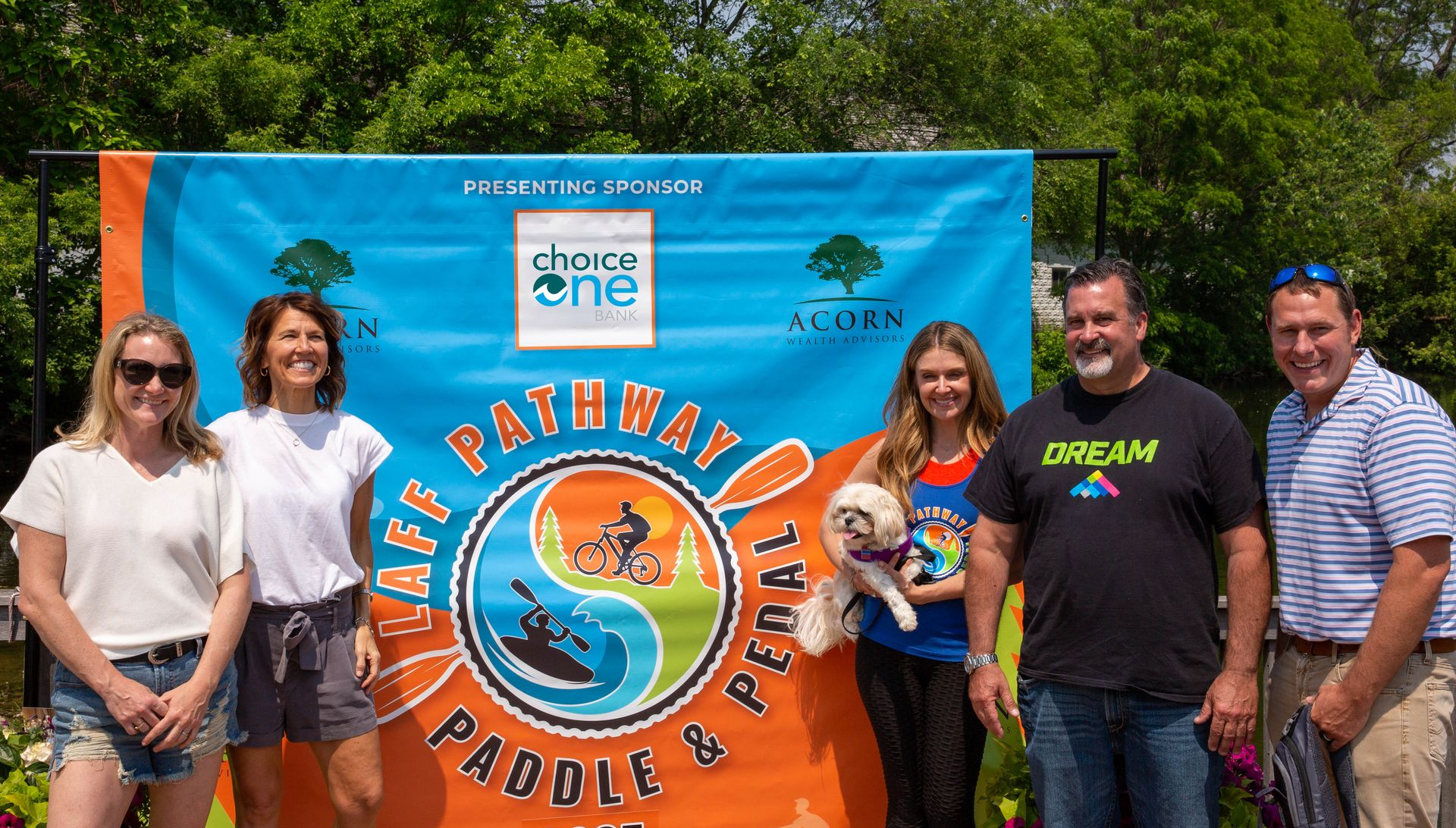 A group of people standing in front of a sign that says paddle and pedal