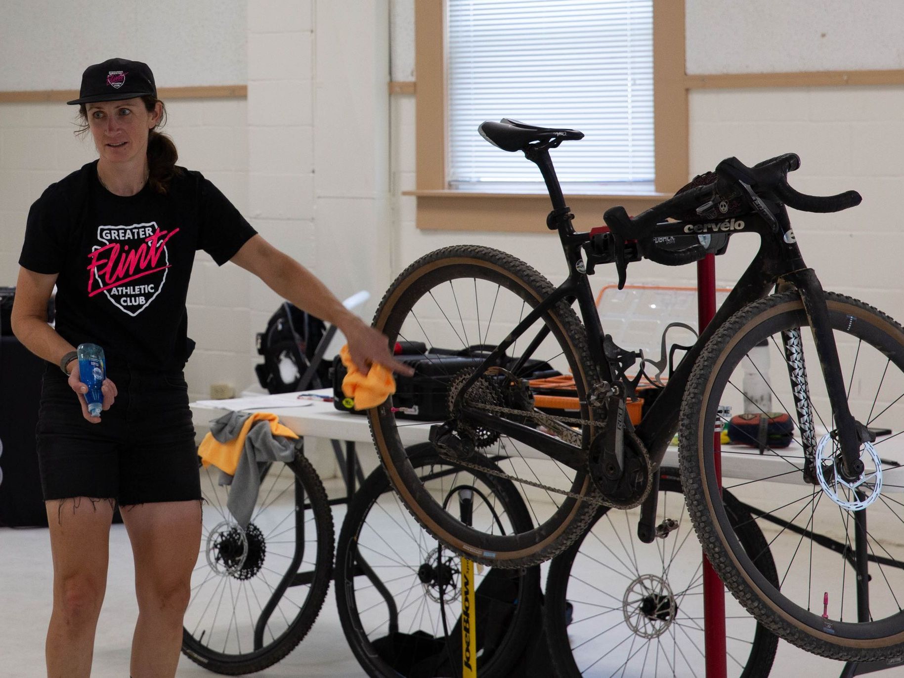 A woman is cleaning a bicycle in a workshop